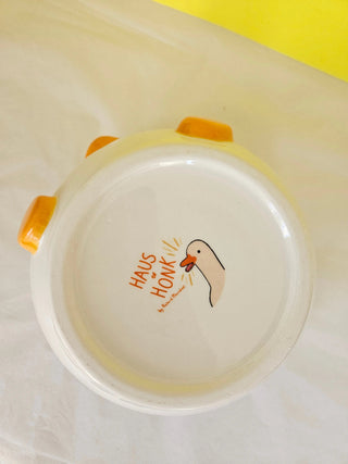 Round white container with orange accents and 'Haus of Honk' branding on a yellow background