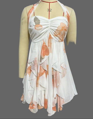 Mannequin wearing a white dress with orange floral patterns in a storage or warehouse setting.