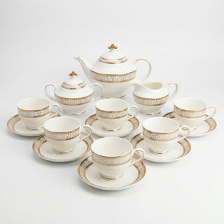 Tea set with white cups and saucers, teapot, and creamer on a light gray background