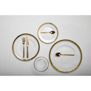Set of gold-rimmed plates with cutlery on a white surface