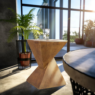 Wooden side table with a glass of water on a patio with plants and a large window in the background.