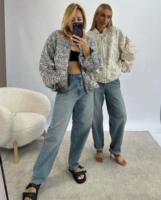 Person wearing a sequin jacket and jeans taking a mirror selfie.