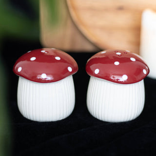 Two ceramic mushroom-shaped salt and pepper shakers on a dark surface.