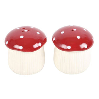 Two mushroom-shaped salt and pepper shakers with red caps and white spots on a white background.