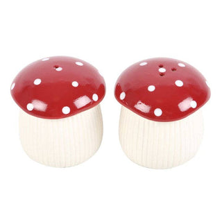 Two mushroom-shaped salt and pepper shakers with red caps and white polka dots on a white background.