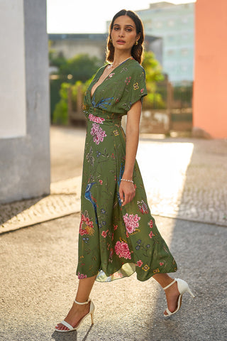Woman wearing a green floral dress standing outdoors.