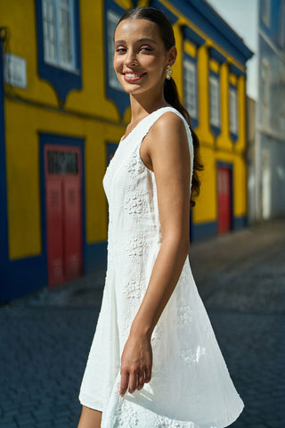 Woman in a white dress standing in front of a colorful building