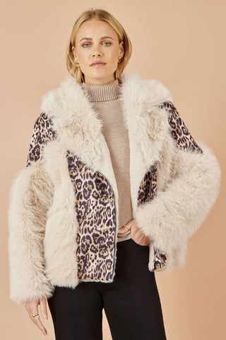 Woman wearing a fluffy white jacket with leopard print patterns on a beige background