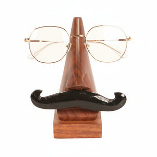 A pair of thin metal-framed eyeglasses displayed on a novelty wooden stand shaped like a nose with a black mustache, against a plain white background.