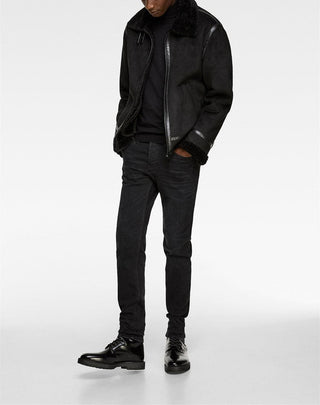Person wearing a black leather jacket, black shirt, black jeans, and black shoes on a white background